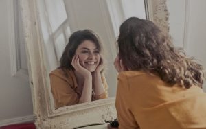 young woman smiling at reflection in the mirror because she looks young again