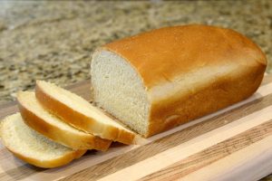 white bread loaf sliced on cutting board