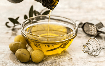 bowl of olive oil with olives beside it