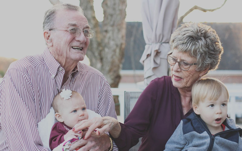 Elderly couple with osteoporosis hold grandchildren