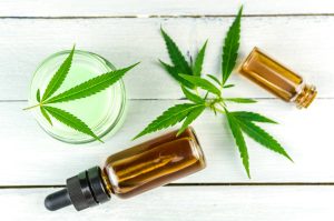 CBD products Cannabis Hemp topical cream and oils balm with cannabis leafs on wooden table