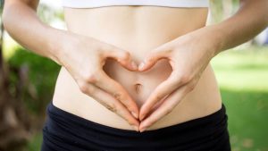 Lady's gut area with her hands in the shape of a heart over it