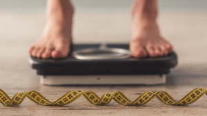 person standing on scale with tape measure in front