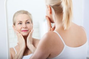 woman looking at skin in mirror