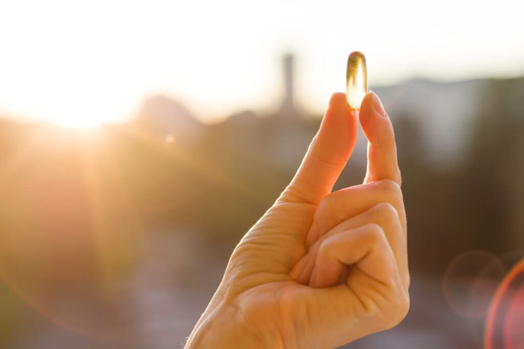 holding vitamin d capsule while standing in the sun