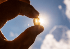 vitamin d supplement in someone's hand looking at the sun